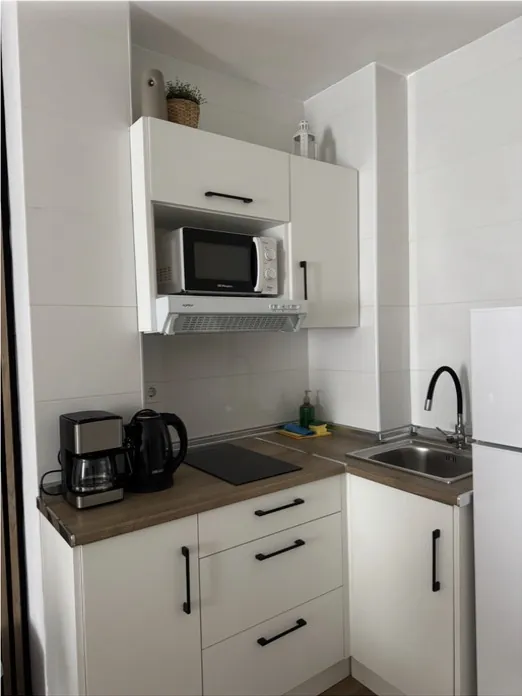 Cocina blanca con encimera de madera y menaje ordenado