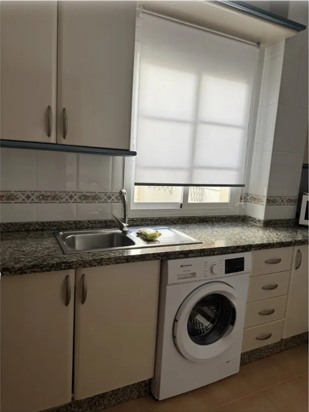 Cocina con encimera de granito y lavadora, limpia