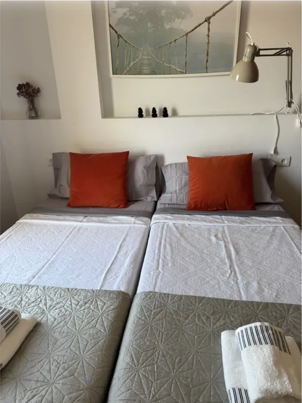 Dormitorio con dos camas y cojines naranjas, listo para los huéspedes