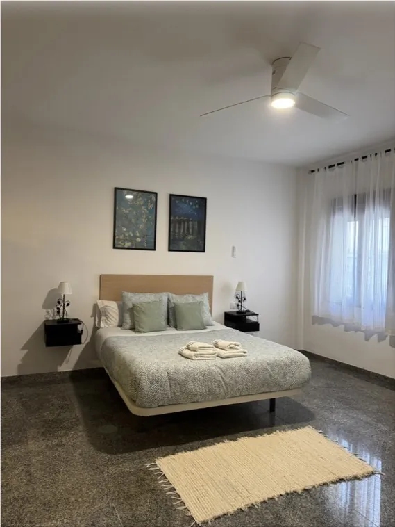 Dormitorio con la cama hecha y cojines verdes