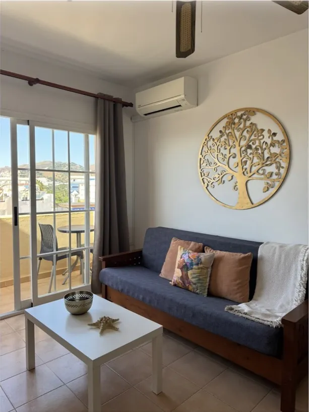 Salón con sofá, mesa de centro y puerta al balcón