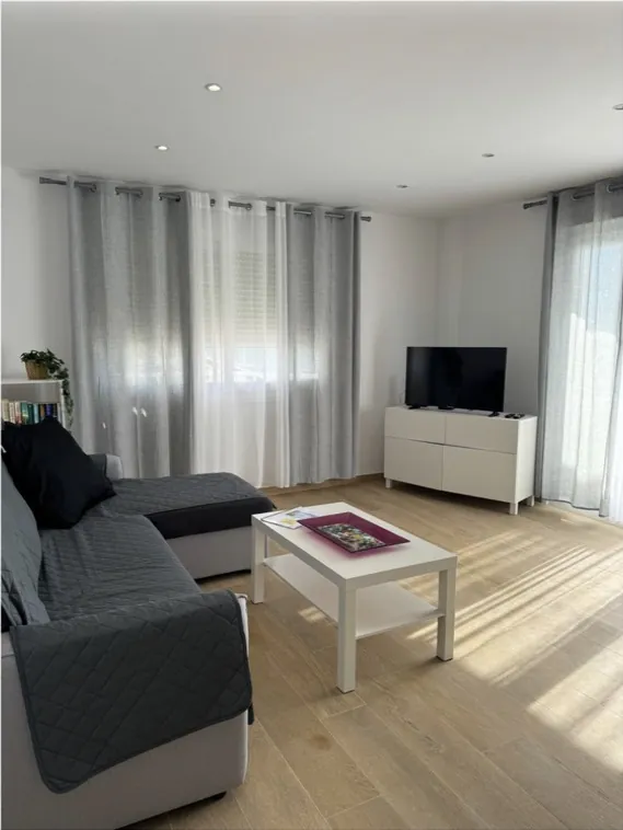Salón luminoso con sofá gris y cortinas